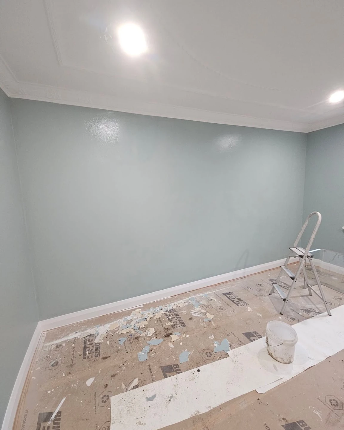 Pale green painted walls with white ceiling and skirting during decorating