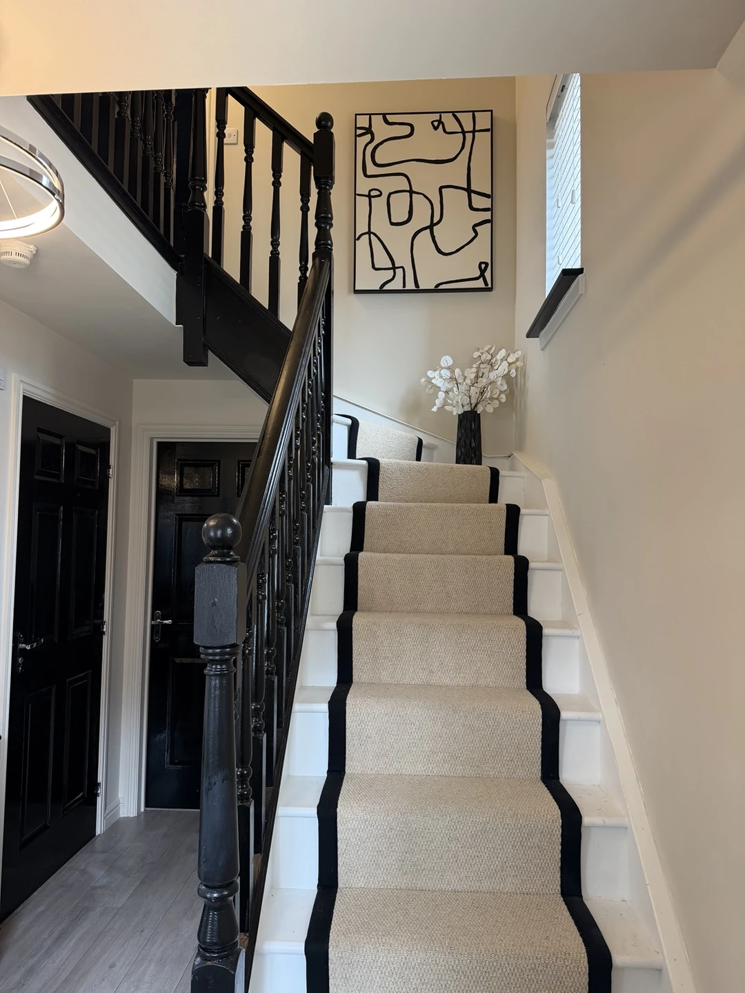 Decorated staircase with black banister, neutral walls and white stair edges