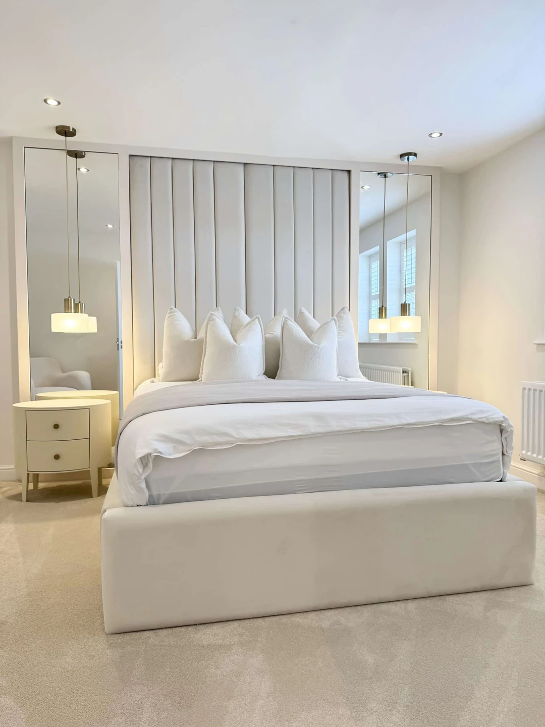 Tall upholstered headboard with mirrored side panels and pendant lighting