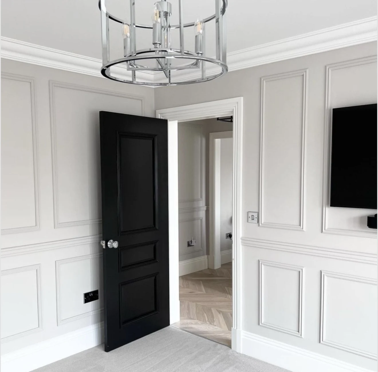 White decorative wall mouldings with a contrasting black painted door